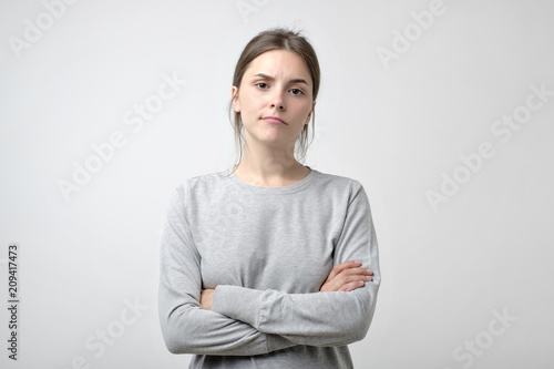 Fotografía Frustrated young woman with crossed hands stands isolated on white