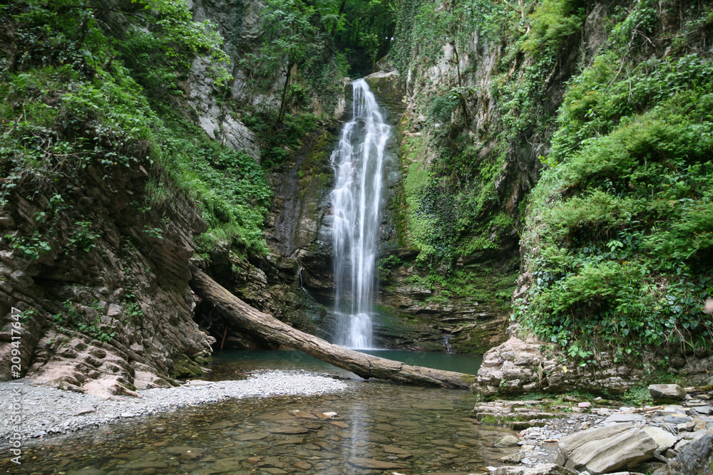The Agek waterfall falls from a cliff into a mountain lake, Sochi
