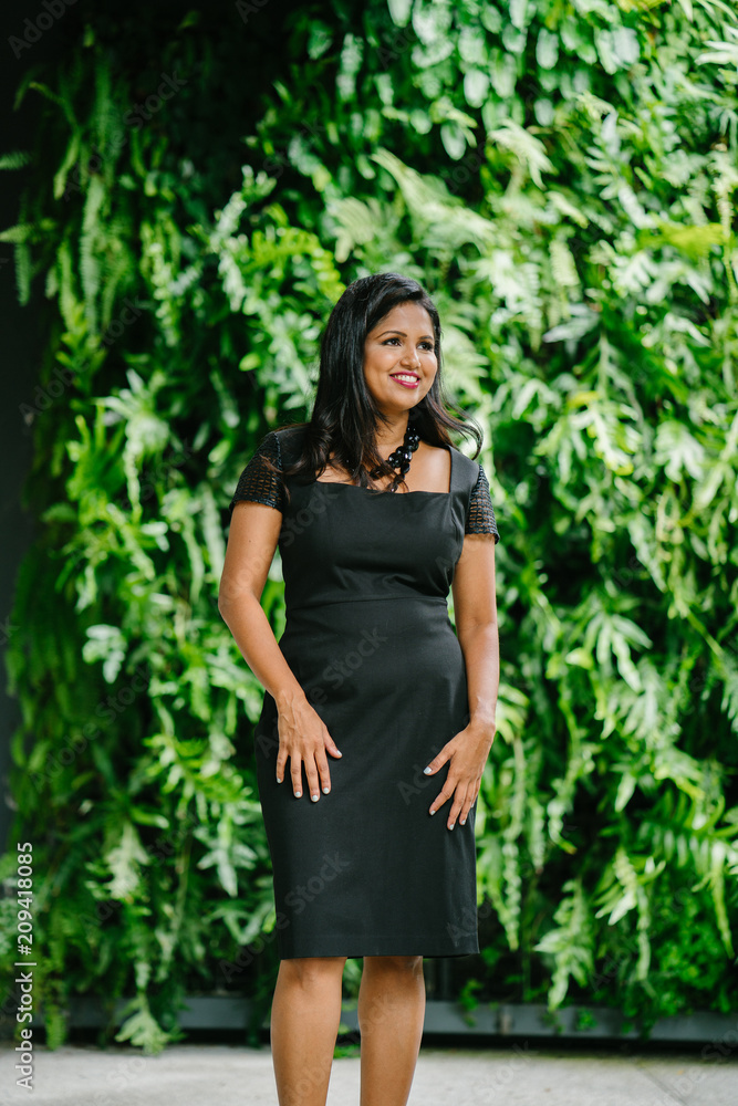 An Indian Asian leader standing beside fresh green plants and confidently striking a pose to show her elegant outfit. An Indian Asian leader standing beside fresh green plants and confidently striking a pose to show her elegant outfit.