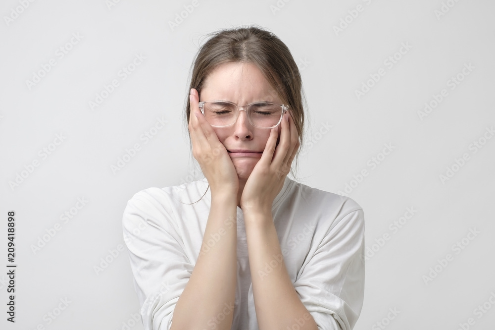 Woman in modern glasses covering ears and shouting. Woman in modern glasses covering ears and shouting.