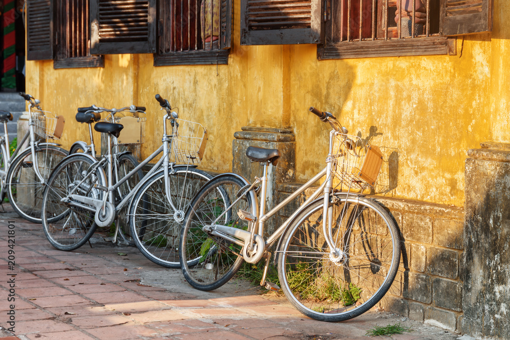 Bicycles parked at yellow wall of old house. Hoi An