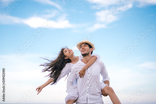 Happy relaxing couple in love on beach summer vacations. Joyful girl piggybacking on young boyfriend having fun.