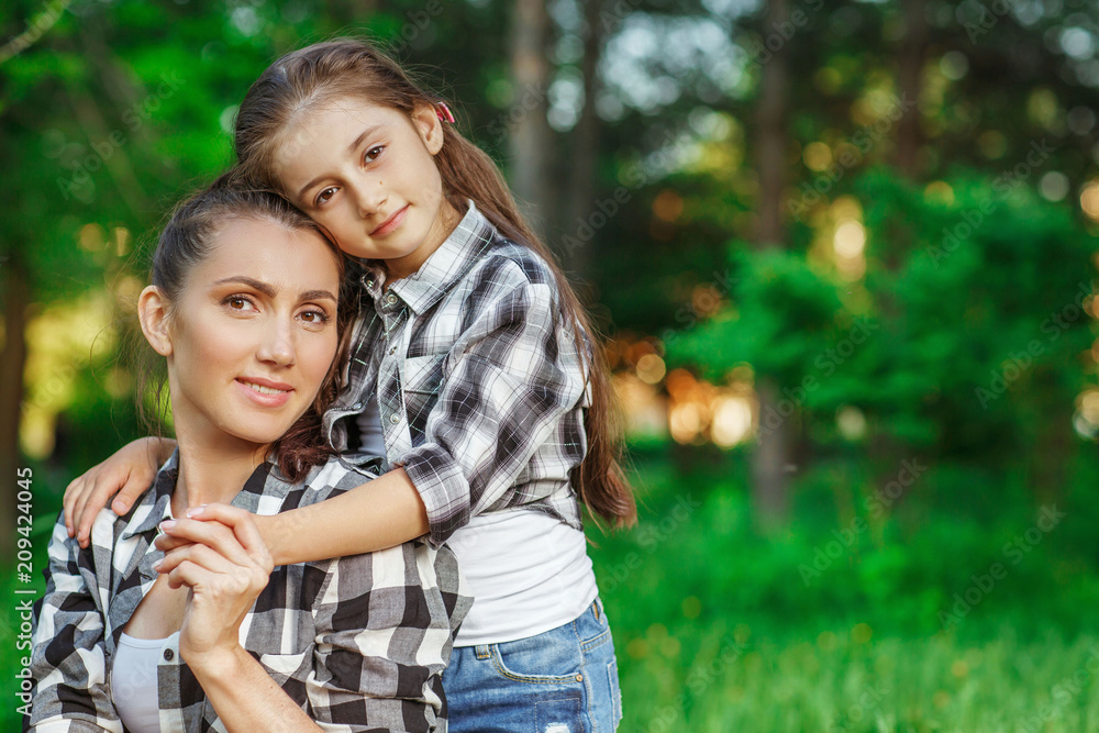 Fototapeta premium Mother and daughter walking in a park on summer day