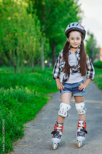 Little girl learning to roller skate outdoors on a summer day
