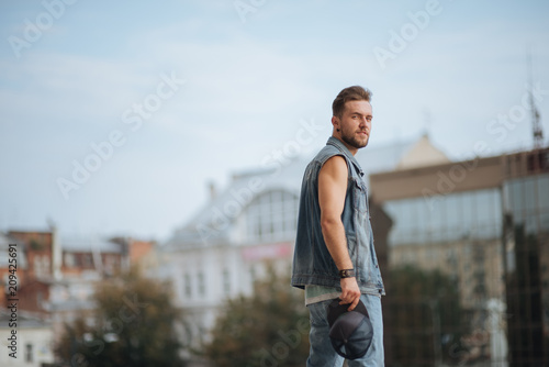 Cheerful young man with a beard outdoors portrait. Enjoying his street style and urban fashion. Dancing man with beard. Wearing black cap.