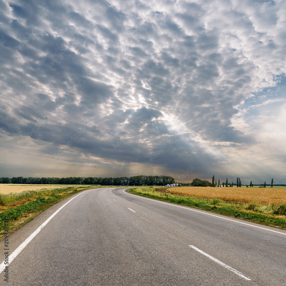 dramatic clouds over asphalt road to horizon dramatic clouds over asphalt road to horizon