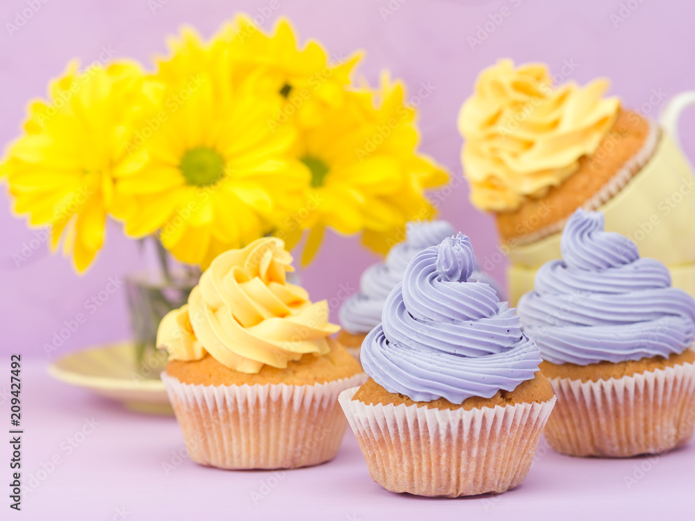 Cupcakes decorated with yellow and violet cream and chrysanthemums on violet pastel background for greeting card with copyscape. Cupcakes decorated with yellow and violet cream and chrysanthemums on violet pastel background for greeting card with copyscape.