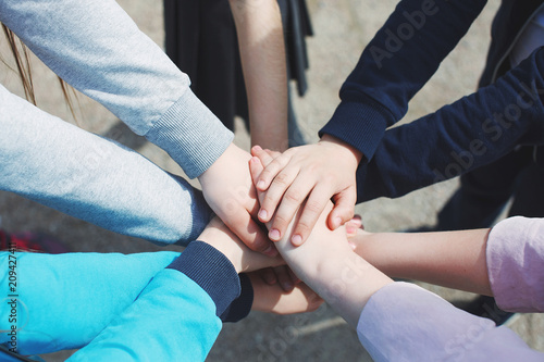 A group of teenagers have many hands connected. The concept of teamwork and unity. © olgasparrow