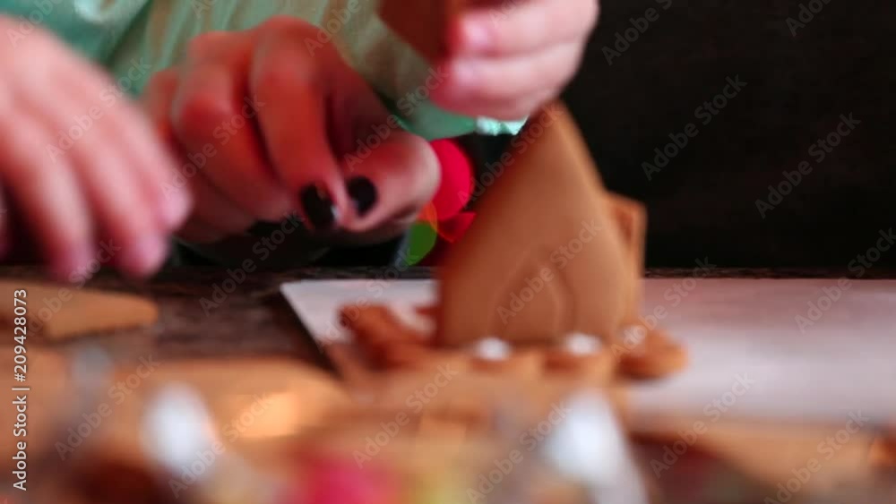Mother and daughter making gingerbread cookies house, decorating at home in front of the Christmas tree, child playing and enjoying, Christmas concept Mother and daughter making gingerbread cookies house, decorating at home in front of the Christmas tree, child playing and enjoying, Christmas concept