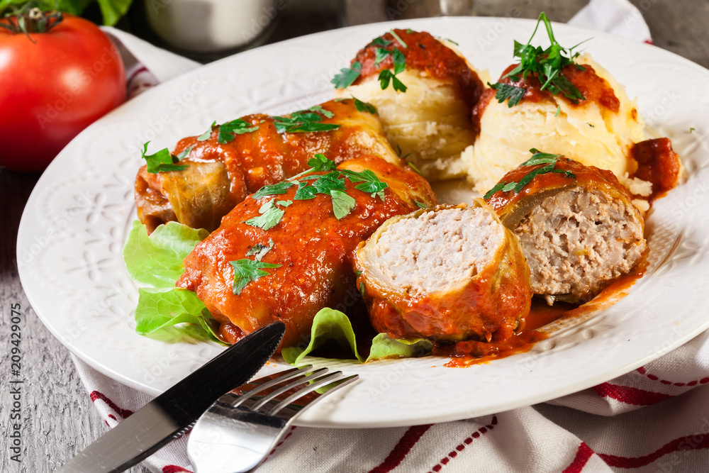 Stuffed cabbage with meat and rice served with boiled potatoes and tomato sauce