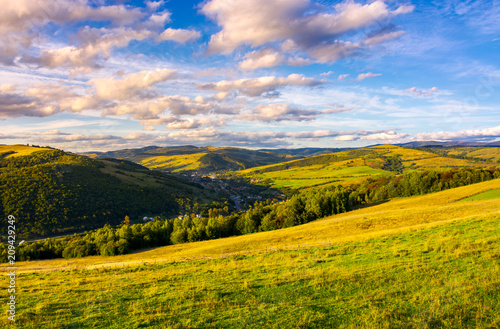 beautiful Carpathian countryside at sunset. village down in the valley in shade of a nearby mountain. beautiful colorful sky with clouds. Great water dividing ridge in the far distance