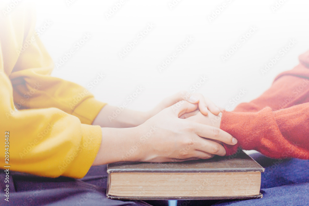 Obraz premium Mentor holding hands encouraged and prayer together on the bible.