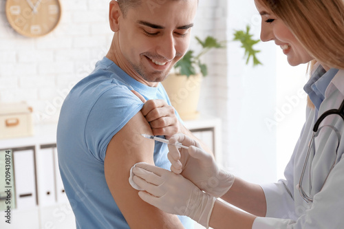 Doctor vaccinating male patient in clinic photo