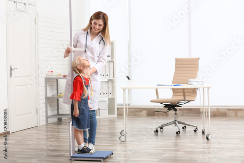 Doctor measuring little girl's height in hospital photo