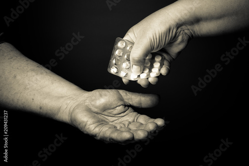 Hands of elderly and young women on black background. Toned