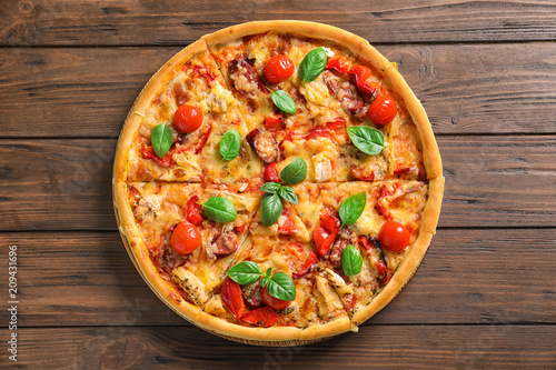 Delicious pizza with tomatoes and sausages on wooden table, top view