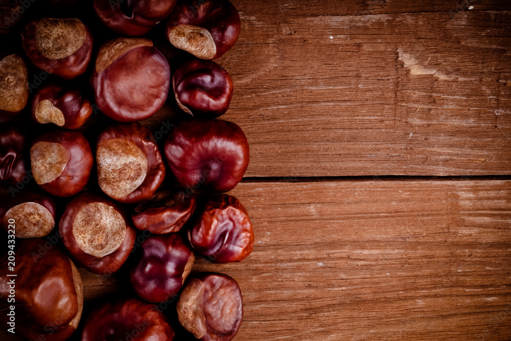 Obraz premium Lot of chestnuts on the old wooden background. Toned