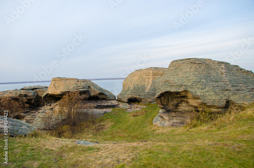 a large stone under the blue sky, near the lake at sunset,