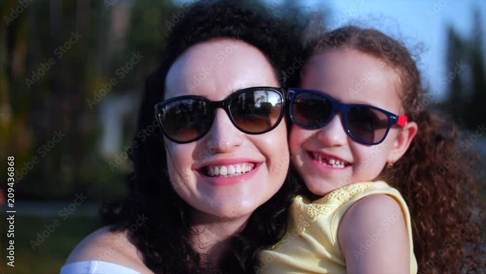 Daughter in the arms of the mother on the street, smiling look at the camera, close-up. Slow motion. Daughter in the arms of the mother on the street, smiling look at the camera, close-up. Slow motion.