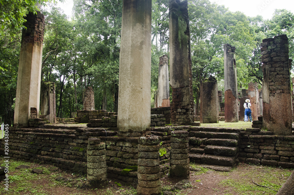 Fototapeta premium Travelers thai woman walking visit and travel take photo in ancient building and ruins of Kamphaeng Phet Historical Park