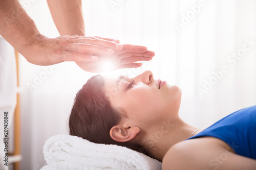 Therapist Performing Reiki Healing Treatment On Woman
