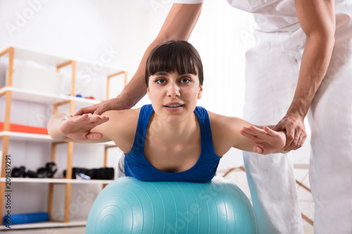 Physiotherapist Assisting Woman While Doing Exercise