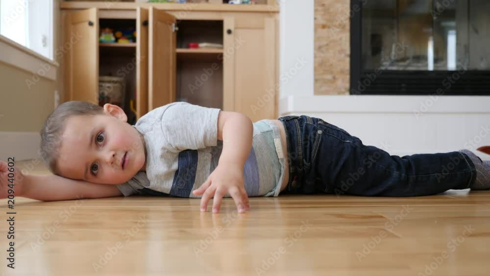 A dolly shot of little boy lying on the floor in a house A dolly shot of little boy lying on the floor in a house
