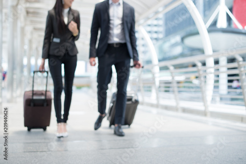 blurred background of businessman and businesswoman walk together with luggage on the public street, business trip concept and copy space for text photo