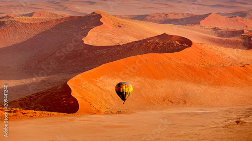 Hot air balloon in flight against orange sand dunes in Sossusvlei Namibia photo