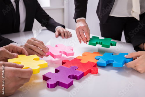 Group Of Businesspeople Solving Jigsaw Puzzle