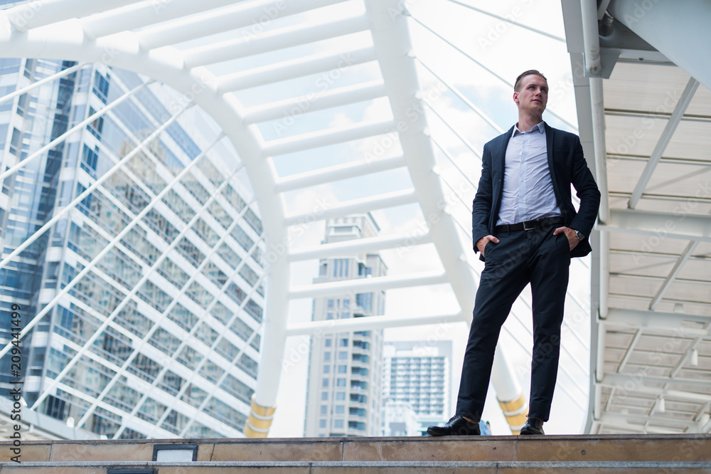 Caucasian businessman stand and smile, he looking forward and thinking for successful in career and mission. concept of winner and competition with copy space for text. Caucasian businessman stand and smile, he looking forward and thinking for successful in career and mission. concept of winner and competition with copy space for text.