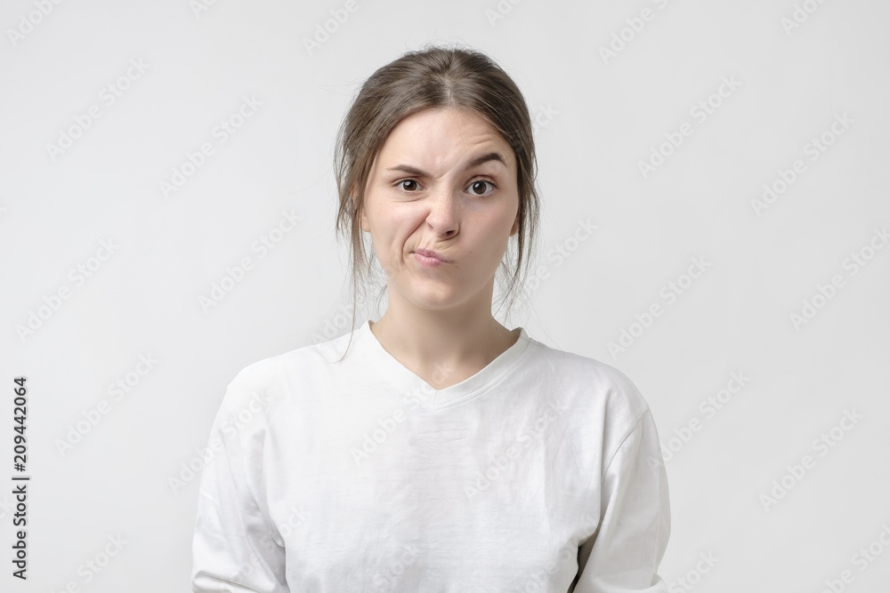 Negative human emotions and feelings. Grumpy young, frowning eyebrows, her look and grimace expressing anger Negative human emotions and feelings. Grumpy young, frowning eyebrows, her look and grimace expressing anger