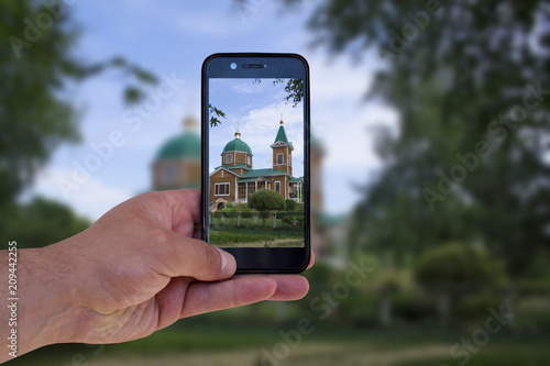 man takes pictures of church on mobile phone