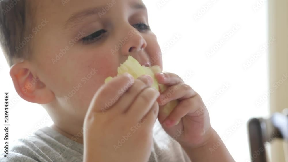 Cute little toddler eats cucumbers with his fingers for a snack Cute little toddler eats cucumbers with his fingers for a snack