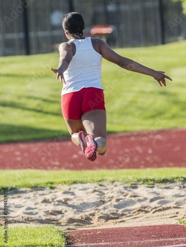 Long triple jumper in the air from behind