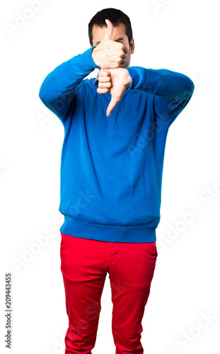 Handsome young man making good-bad sign on white background
