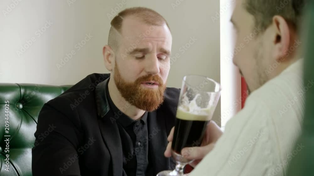 Portrait of redhead man with a beard drinking beer with friends in a pub. 4K Portrait of redhead man with a beard drinking beer with friends in a pub. 4K