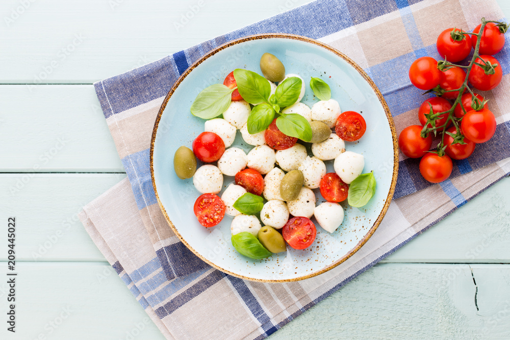 Delicious caprese salad with ripe cherry tomatoes and mini mozzarella cheese balls with fresh basil leaves. Delicious caprese salad with ripe cherry tomatoes and mini mozzarella cheese balls with fresh basil leaves.