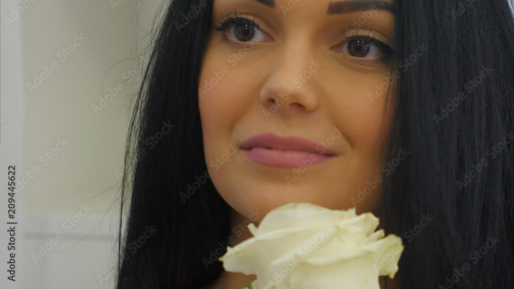 Young woman smells white rose and smiles Young woman smells white rose and smiles