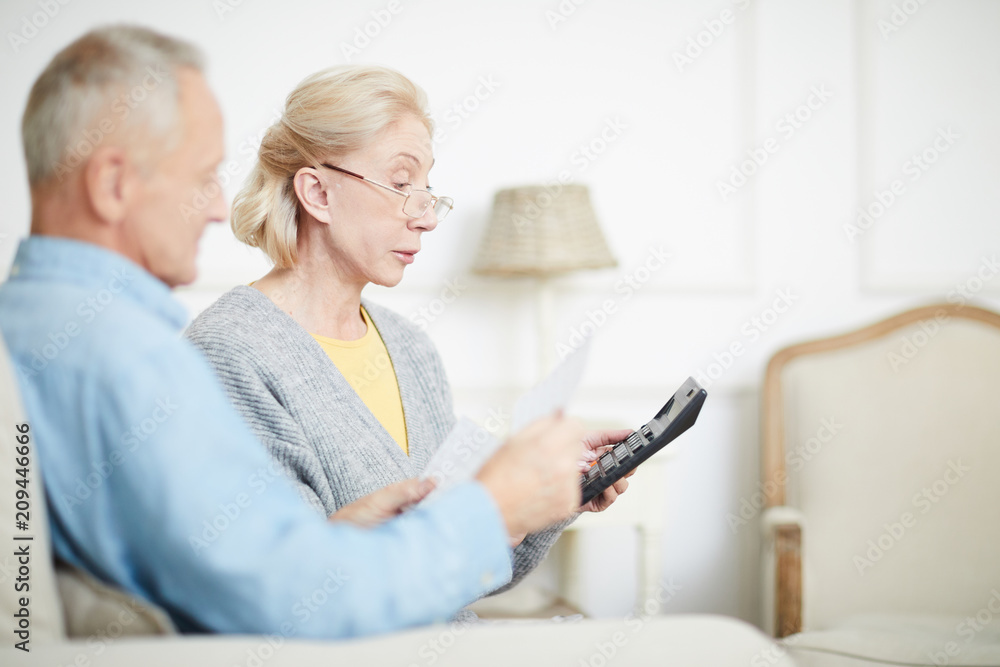 Modern senior couple counting their family budget and expenses using calculator Modern senior couple counting their family budget and expenses using calculator