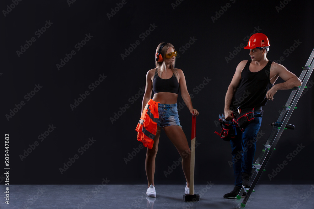 Fototapeta premium Couple builder with construction tools near building ladder