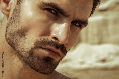 Strong face male model on the nature background with sand and water on the beach on the sunset photo