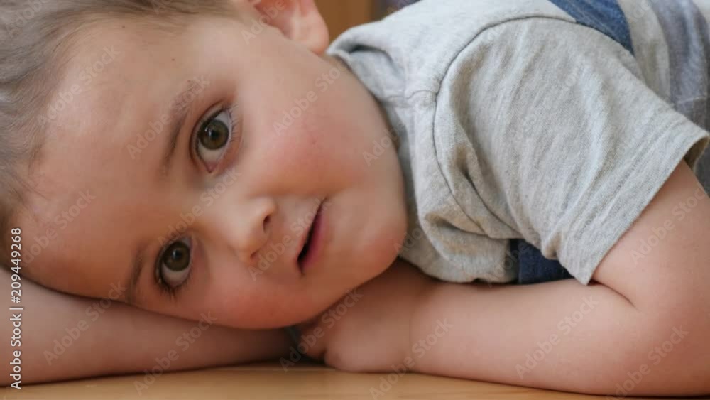 Dolly shot of a happy toddler lying on the floor in his house Dolly shot of a happy toddler lying on the floor in his house
