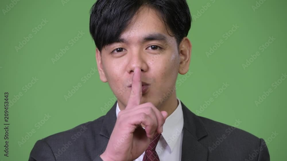 Young handsome Asian businessman with finger on lips Young handsome Asian businessman with finger on lips