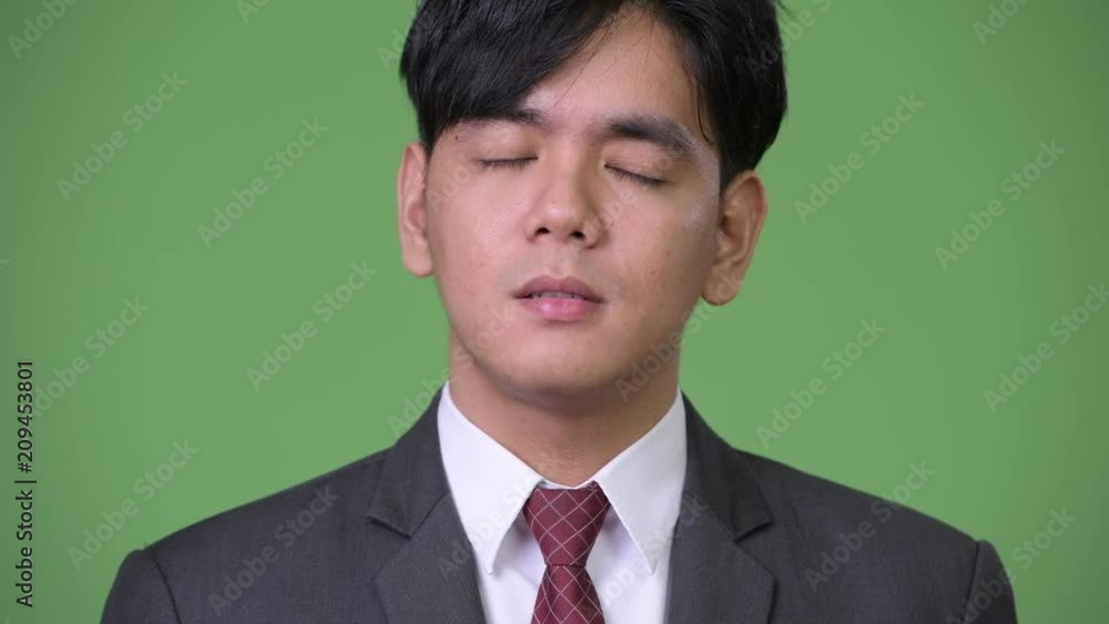 Young handsome Asian businessman looking bored Young handsome Asian businessman looking bored