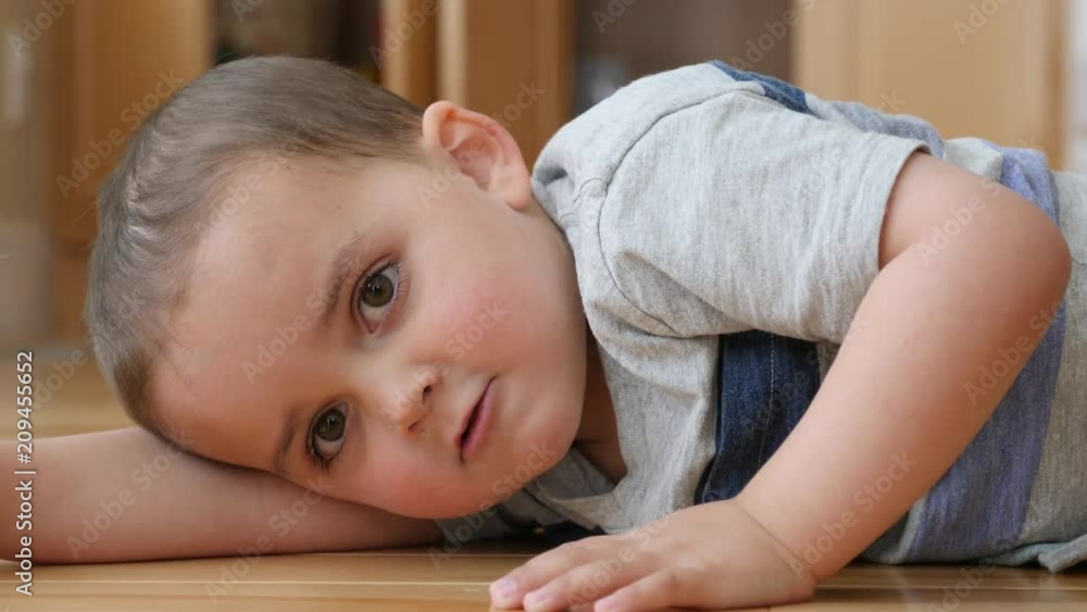Dolly shot of happy toddler lying on the floor in his house Dolly shot of happy toddler lying on the floor in his house