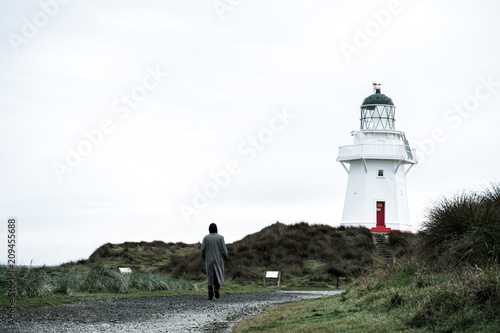 A man walking at Waipapa point, the lighthouse, ocean and cloudy. photo