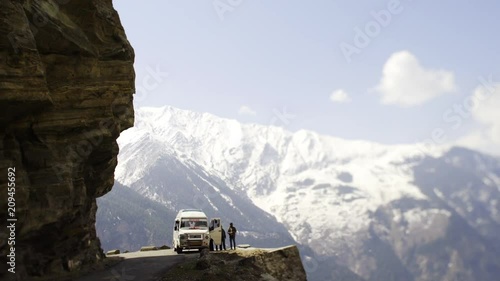 road to kalpa village in rocky mountain, car parking on the very bring, passenger go out from car and looking at beautiful view with high snow peaks at background