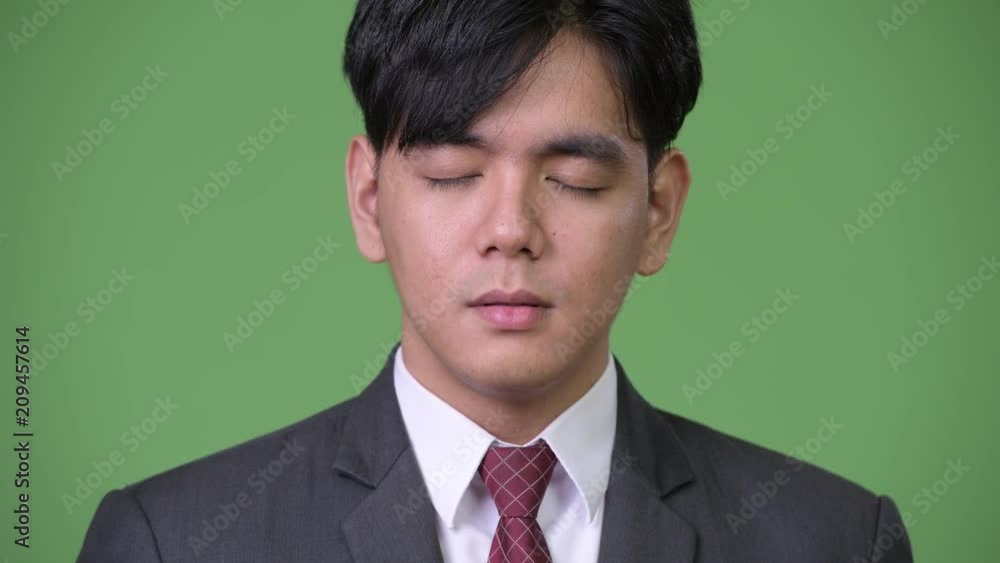 Young handsome Asian businessman relaxing with eyes closed Young handsome Asian businessman relaxing with eyes closed