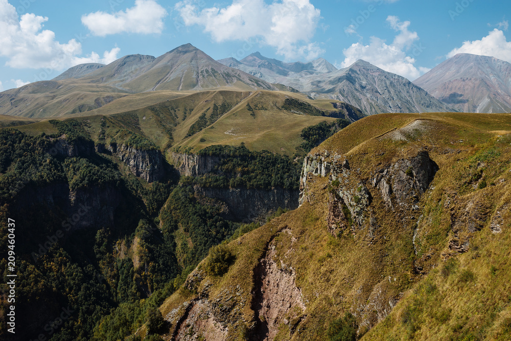 Obraz premium Beautiful rocks, overgrown with green grass. Mountains illuminated by sun. Landscape.